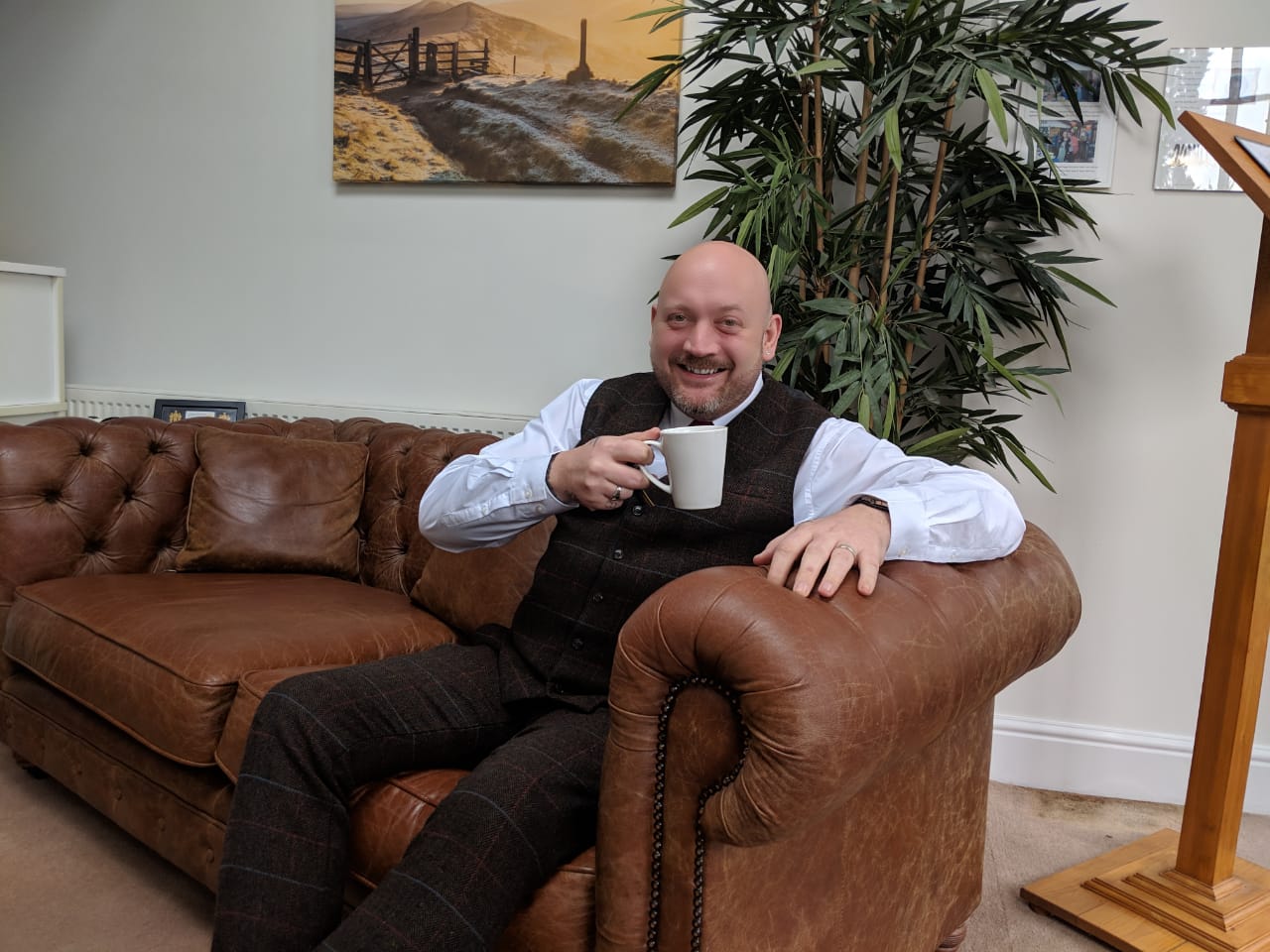 Home manager Matthew Whitfield sitting on a sofa enjoying a cup of coffee